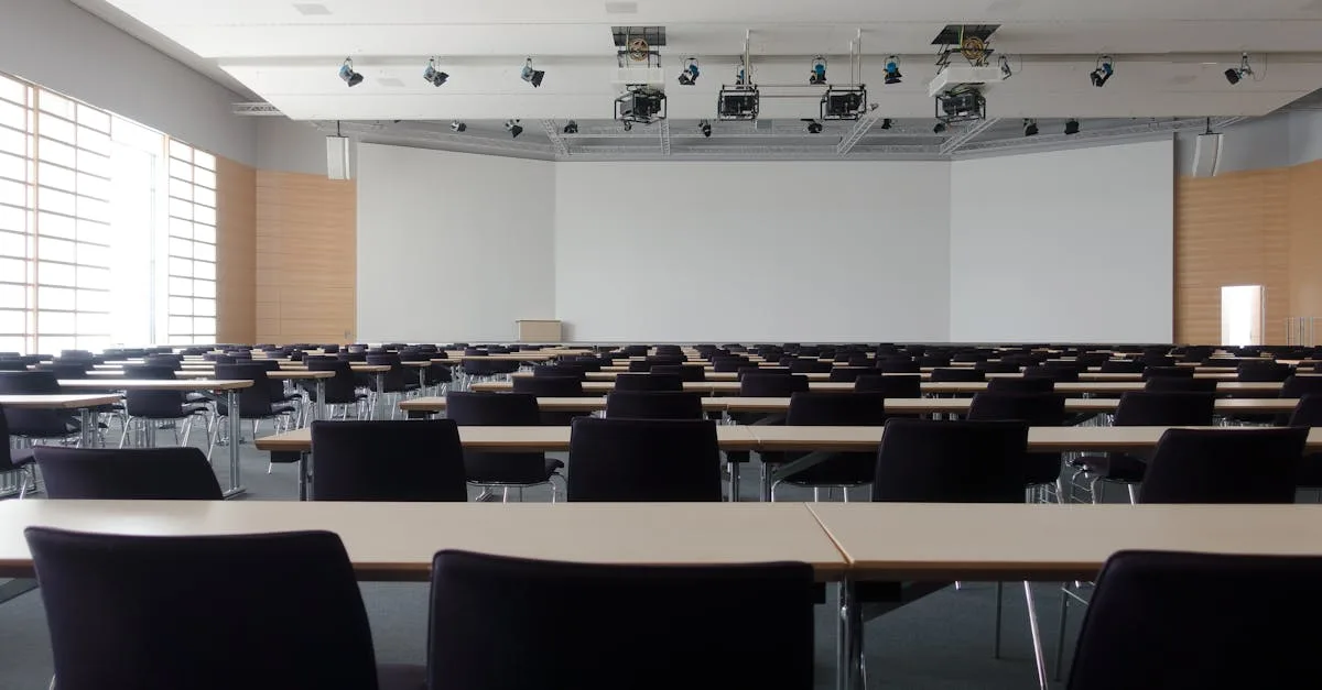 Spacious contemporary conference room with rows of tables and chairs, ready for meetings.