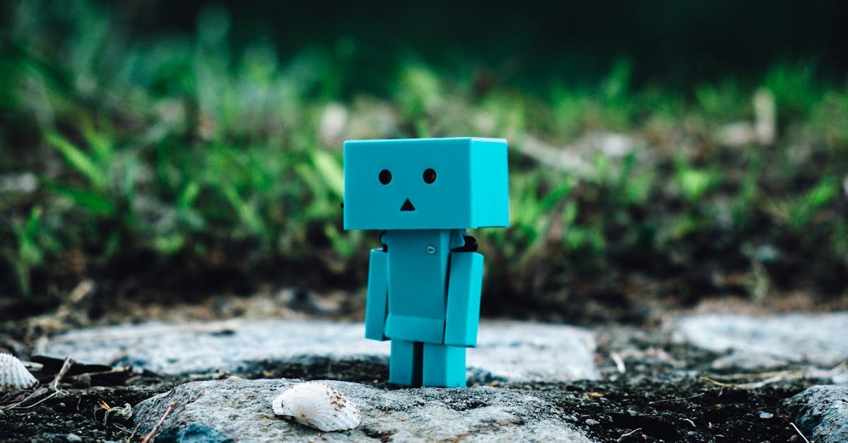 Cute blue toy robot standing on a rocky path surrounded by greenery.