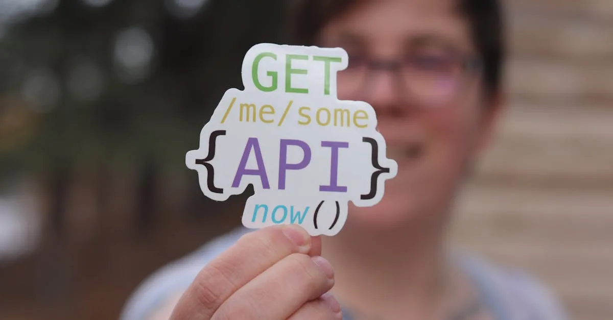 Close-up of a person holding a colorful API-themed sticker with trees blurred in the background.