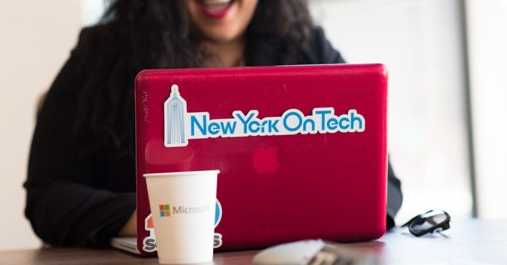 Young woman working remotely with a laptop in a modern indoor office setting, showcasing tech culture.