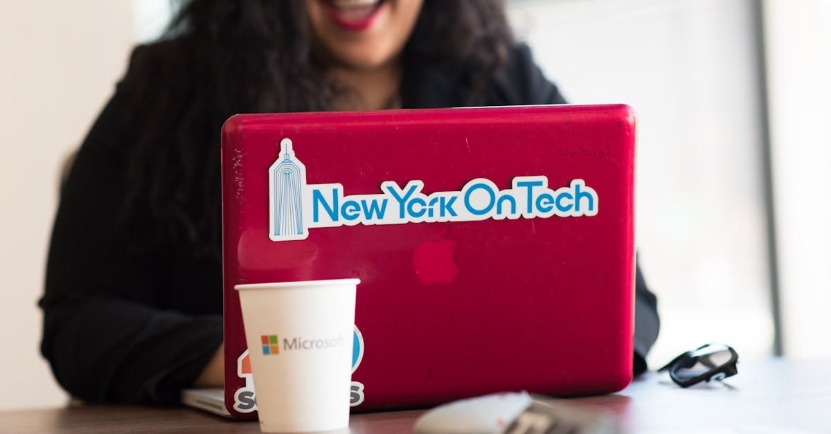 Young woman working remotely with a laptop in a modern indoor office setting, showcasing tech culture.