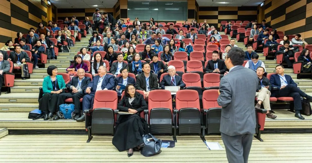 Professional setting of a business conference with attendees and a presenter in an auditorium.
