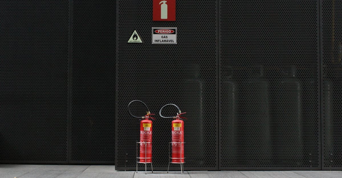 Red fire extinguishers against industrial metal wall with warning signs.