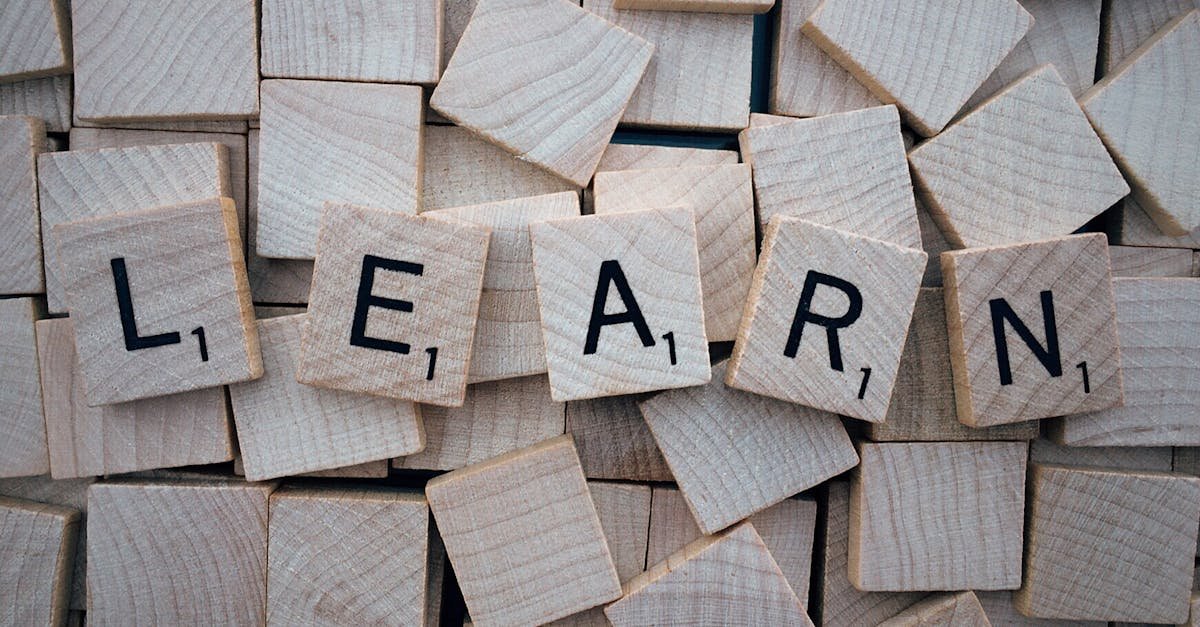 Wooden letter tiles arranged to spell 'learn' on a background of scattered tiles.