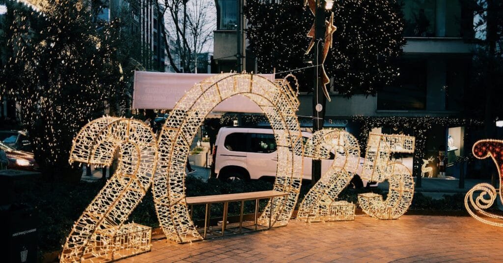 Illuminated 2025 sign on city street with decorative lights creating a festive atmosphere.