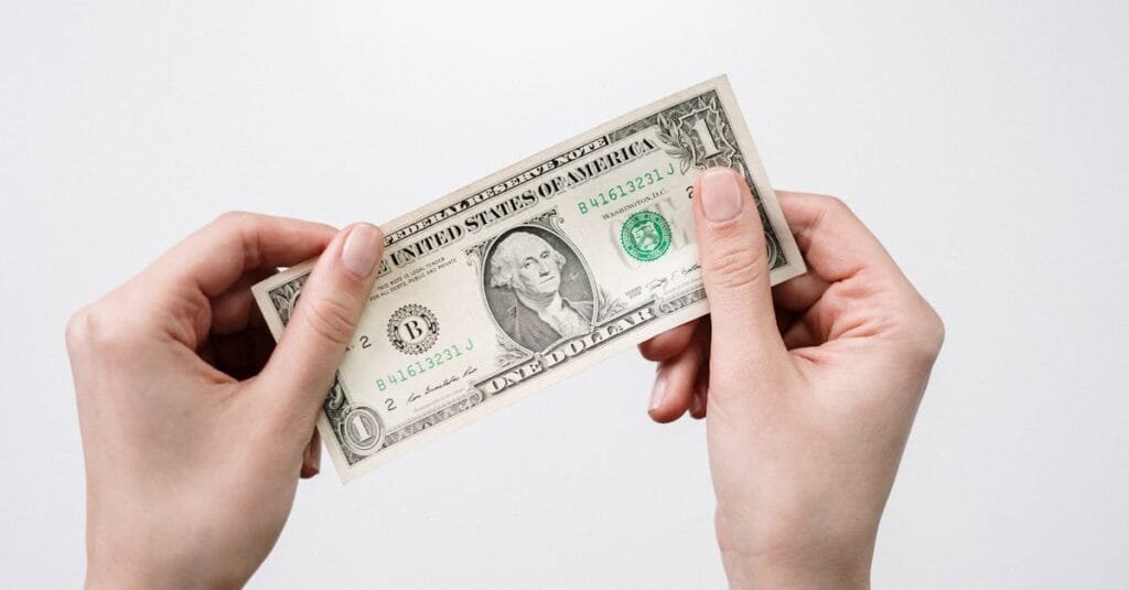 Hands holding a one dollar bill, depicting currency and finance closely.