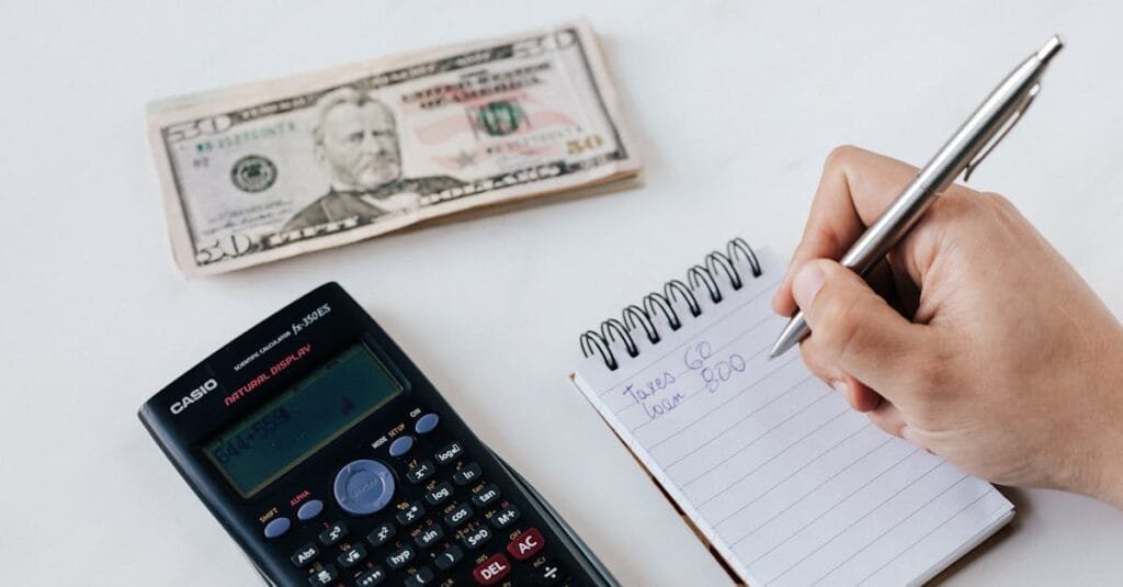 Close-up of budgeting items including calculator, cash, and notebook for financial planning.
