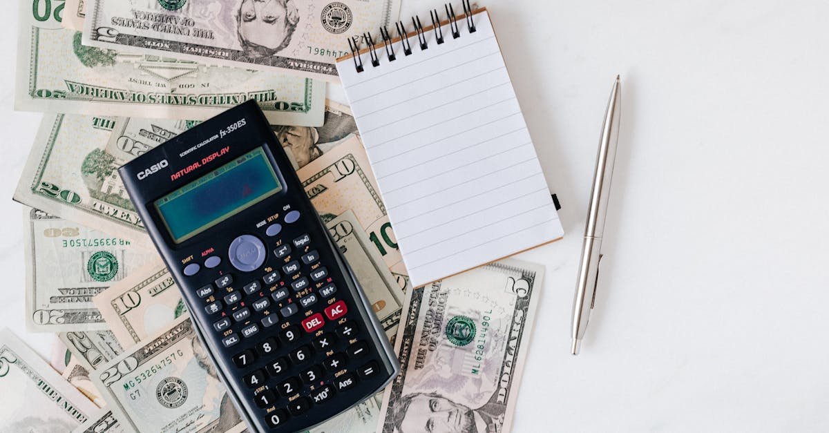 Flat lay of US dollar bills with calculator and notebook for budgeting.