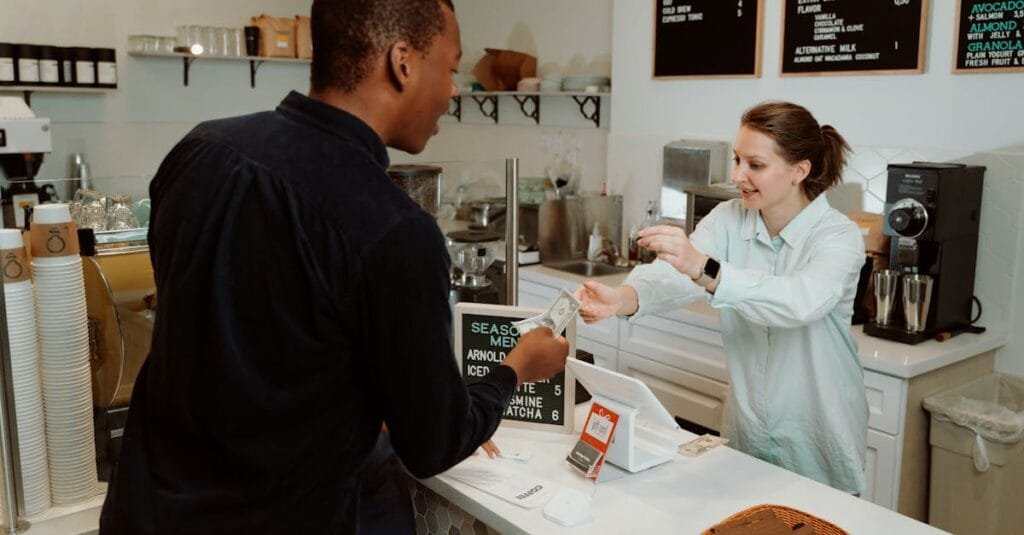 A customer pays for coffee at a café counter, transaction with barista.
