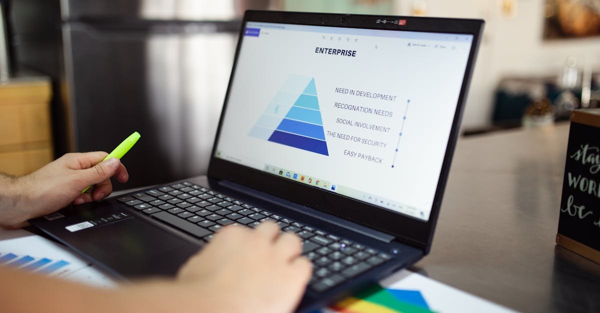 Person analyzes business data on laptop, using pyramid chart and financial reports.