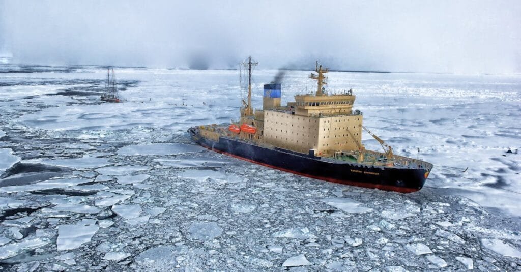 Icebreaker ship cutting through vast frozen ocean, showcasing winter exploration.