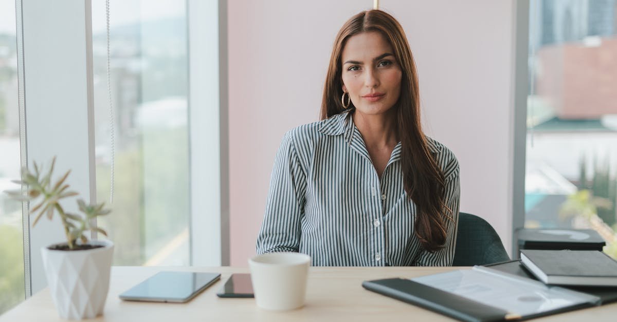 Portrait of a businesswoman with brown hair sitting at a desk in a modern office environment.