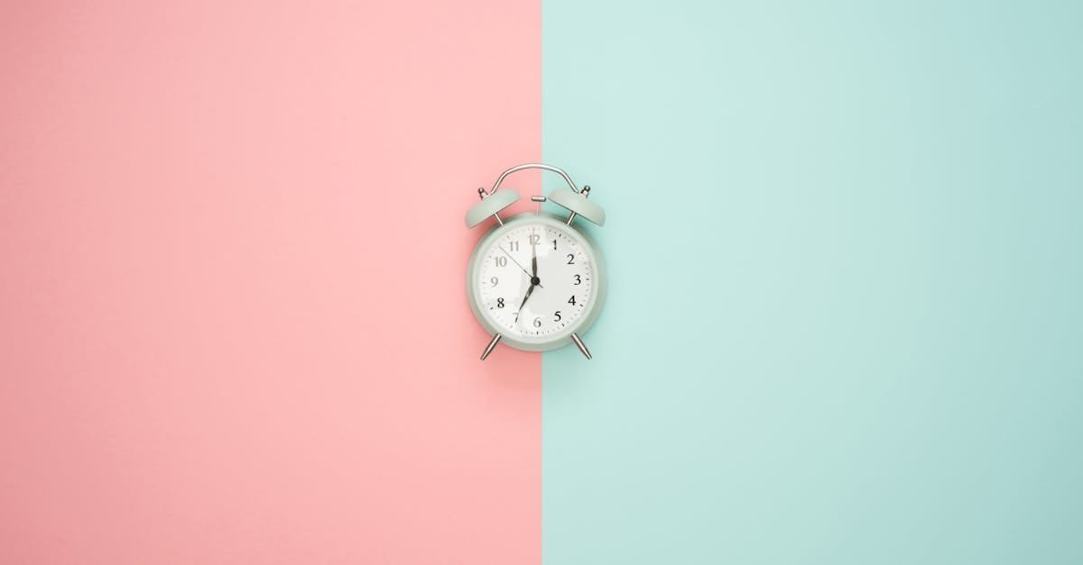 A vintage round clock on a split pastel pink and blue background.