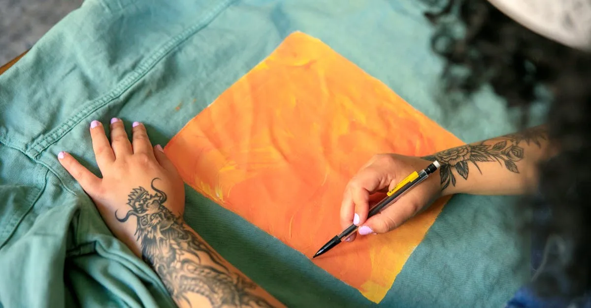 Tattooed artist adds bright orange artwork to a green jacket, showcasing creativity and design.