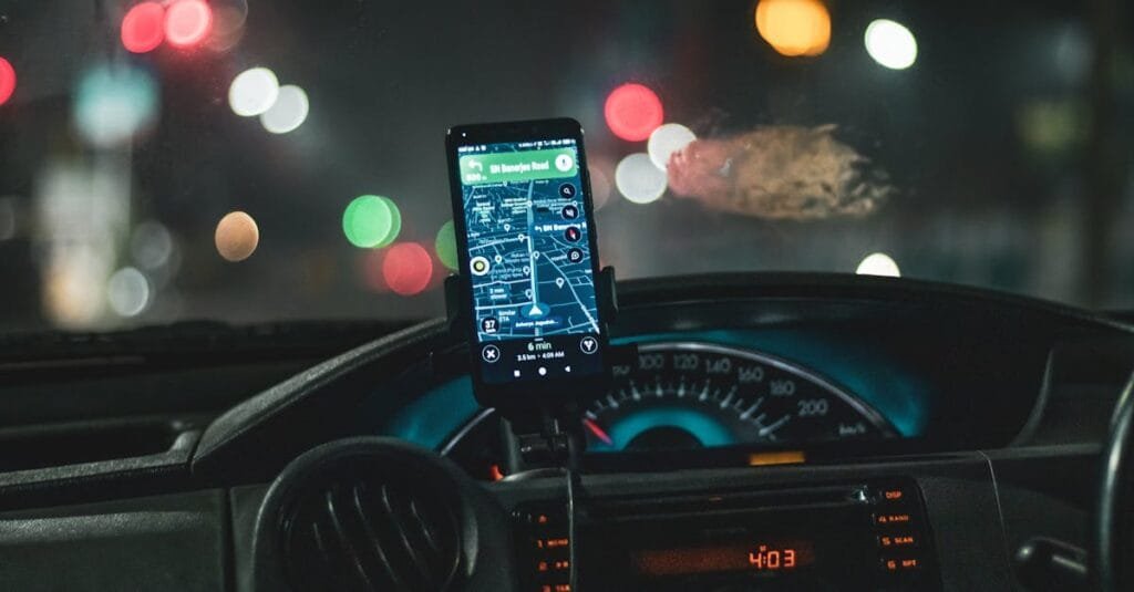 Close-up of a smartphone with map navigation in a car at night with bokeh effect.
