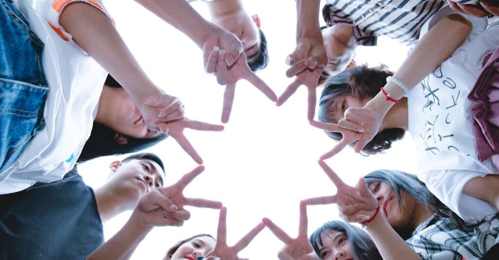 A circle of friends forming a star shape with fingers, symbolizing unity and teamwork.