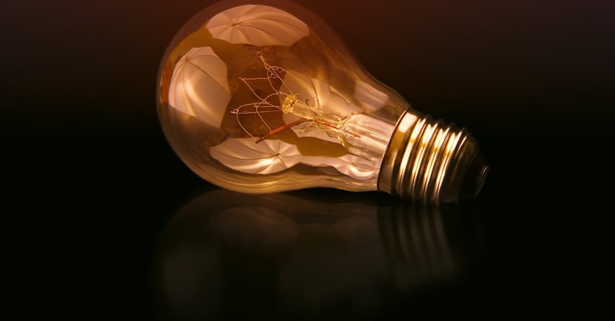 A detailed close-up of a light bulb showcasing its intricate filament and glowing glass against a dark reflective surface.