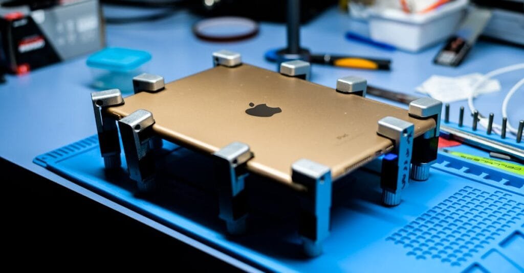 A close-up view of a tablet undergoing repair in a tech workshop with specialized tools.