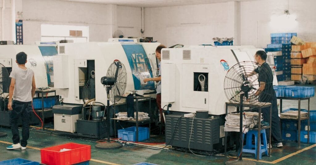 Workers operating machinery in an industrial factory setting, showcasing manual labor and production.