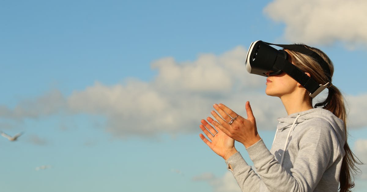 Woman using VR headset outdoors, exploring virtual reality under a clear blue sky.
