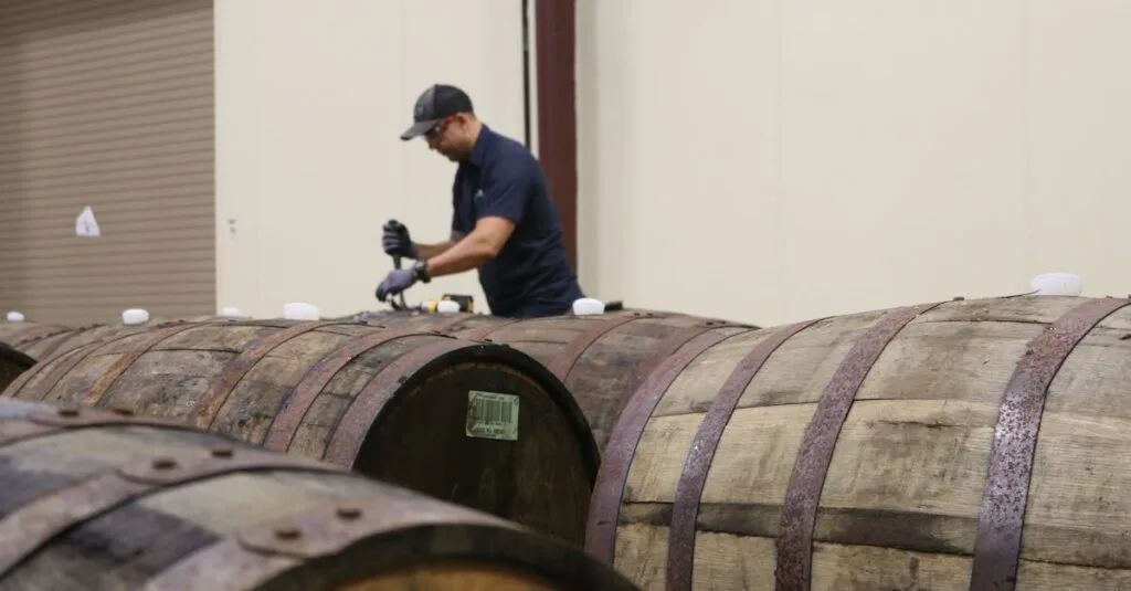 A worker carefully inspecting wooden barrels in a winery room, ensuring quality.