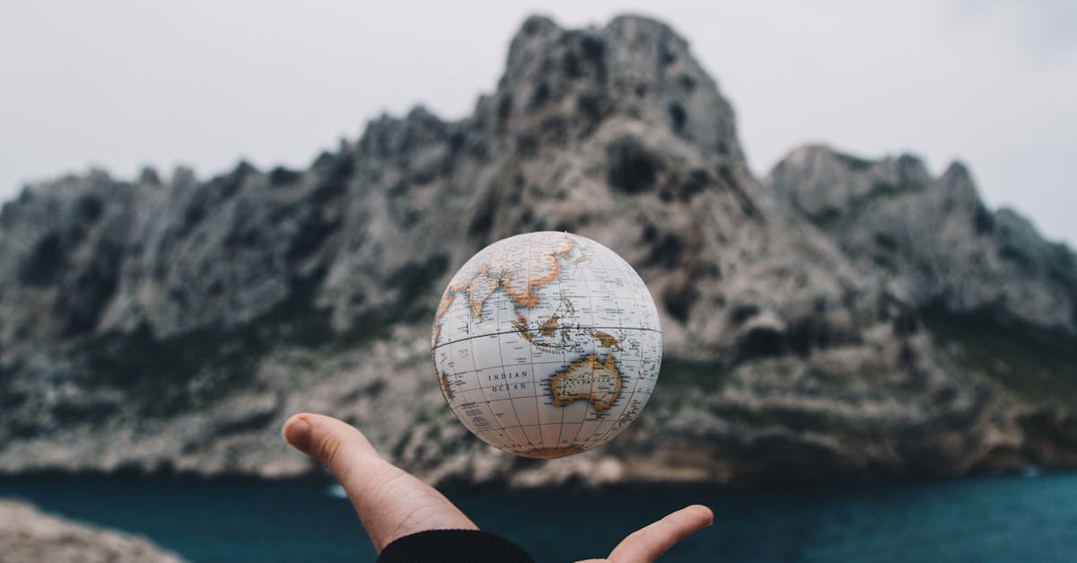 A hand holding a floating globe with a scenic Marseille backdrop, capturing adventure and exploration.