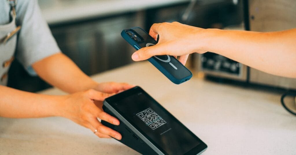 Close-up of a contactless payment using a smartphone and QR code scanner in a modern retail setting.