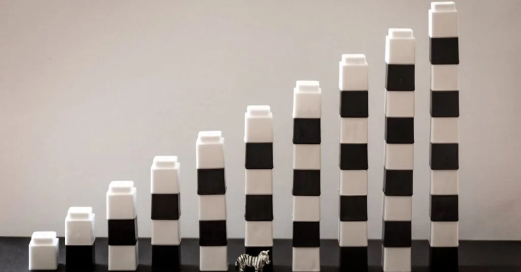 Black and white blocks steadily stacked, forming a gradual rise with a tiny zebra figurine in front.