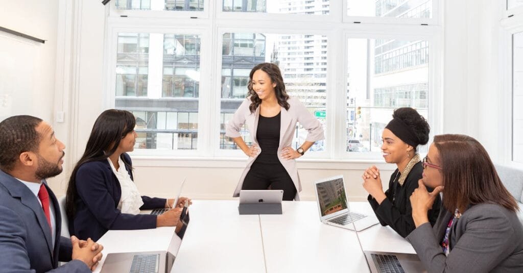 Diverse team engaged in a business meeting with laptops in a modern office setting.