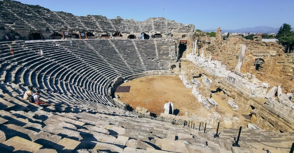 Explore the stunning Roman amphitheater ruins under a clear sky, showcasing ancient architecture.