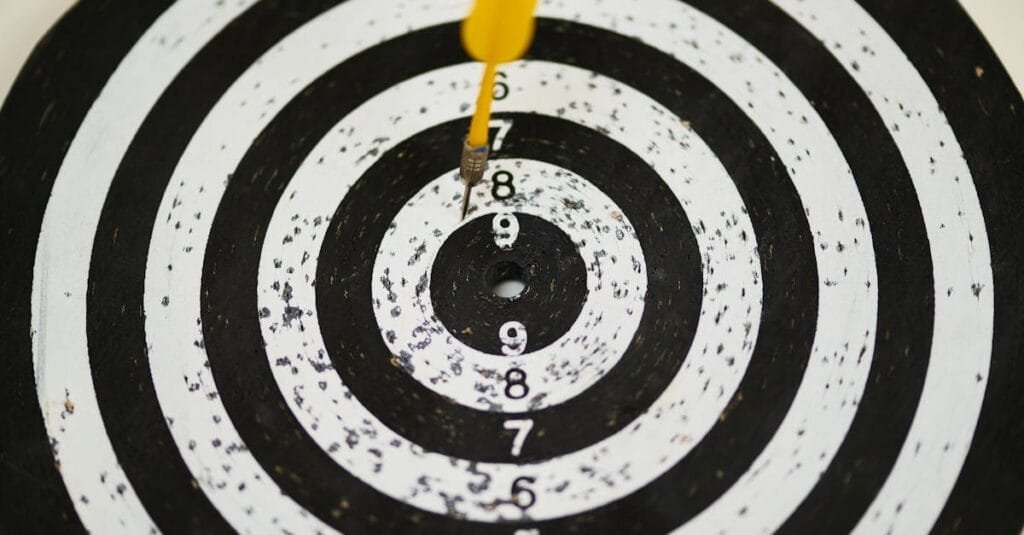 Close-up of a dart hitting the bullseye on a black and white target board symbolizing success.