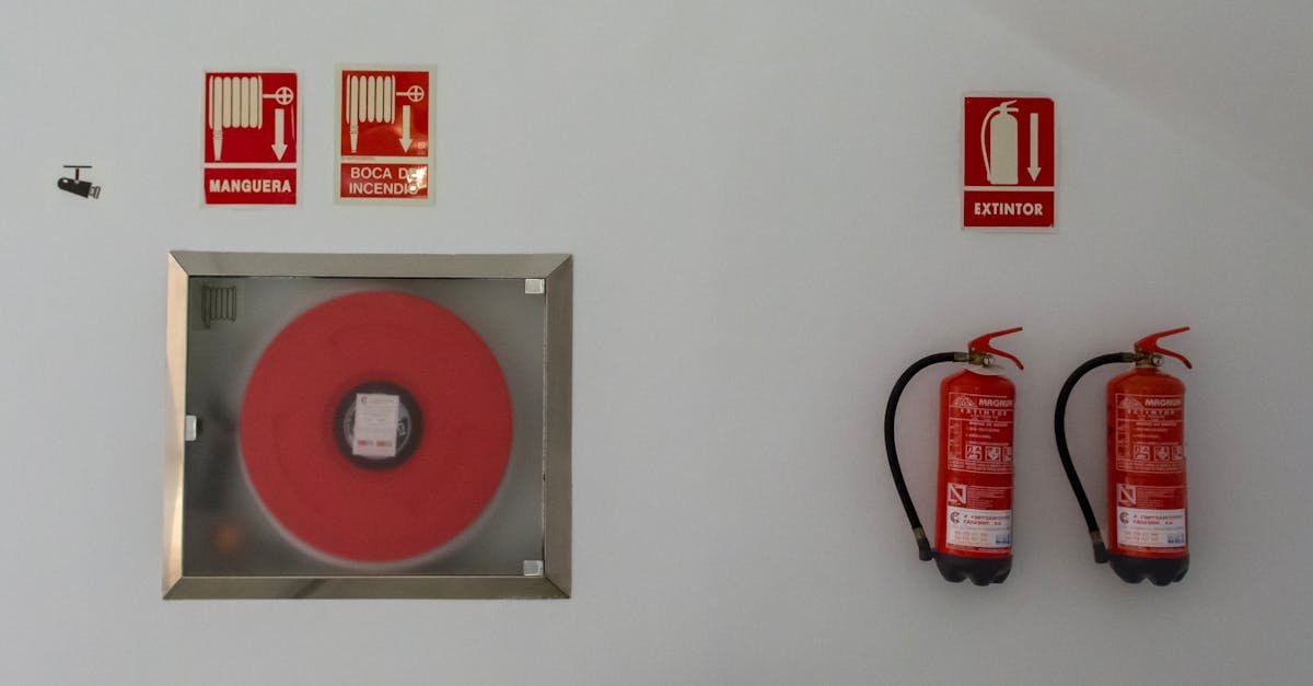 Fire safety setup with extinguishers and hose reel on a white wall for emergency preparedness.