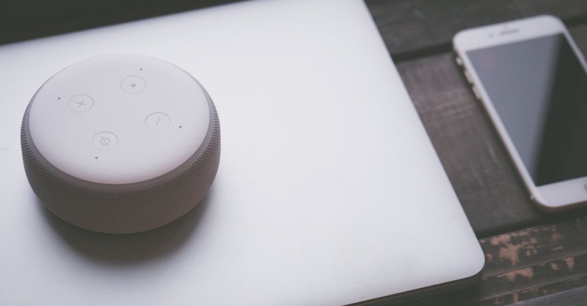 A smart speaker, laptop, and smartphone array representing modern technology lifestyle on a wooden surface.