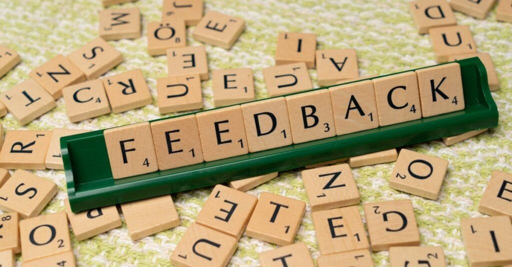 Wooden letter tiles spelling 'feedback' on a green rack, representing communication and evaluation.