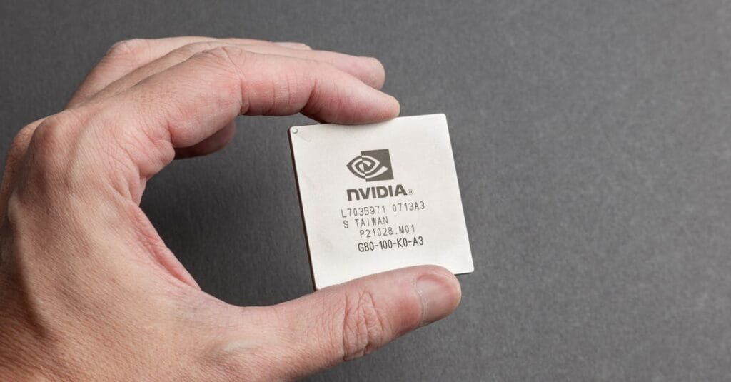 A close-up view of a person holding an Nvidia chip with a gray background.