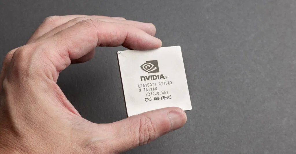 A close-up view of a person holding an Nvidia chip with a gray background.