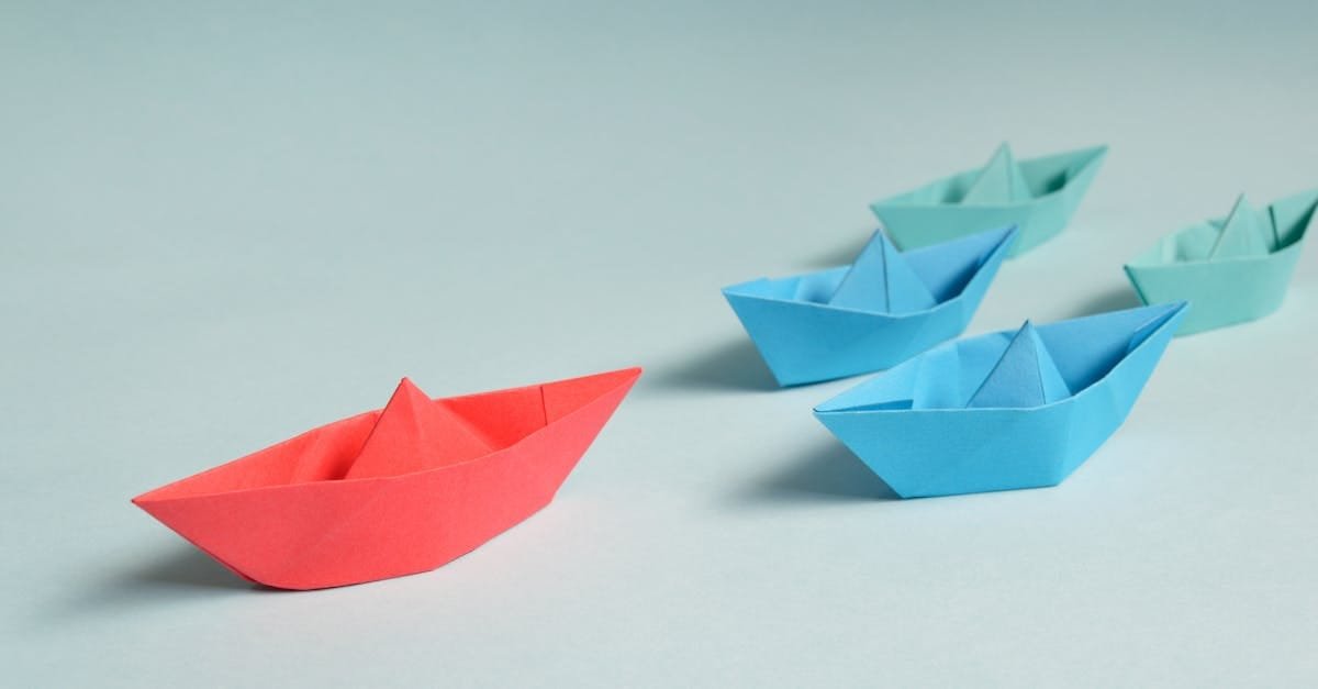Colorful origami paper boats arranged to depict leadership and teamwork concepts.