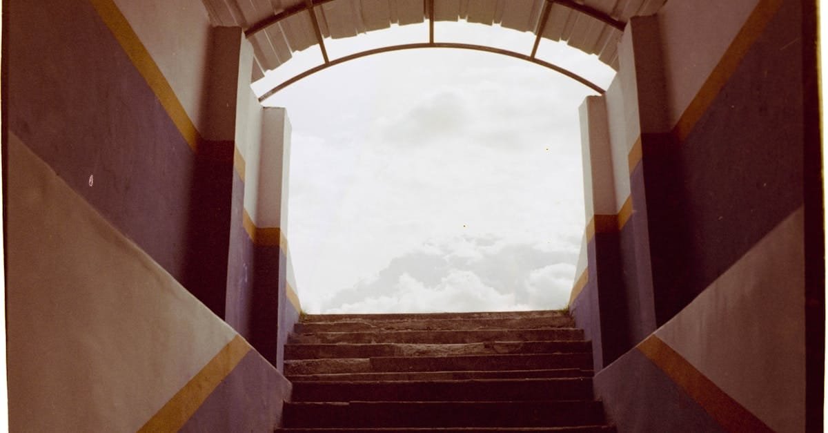 Architectural stairs leading to a bright, cloudy sky, framed by colorful walls.