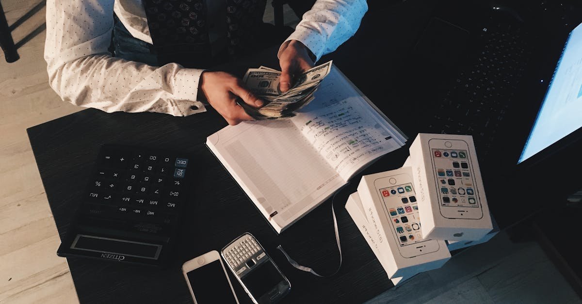 Businessman organizing finances with tech devices and cash on desk.