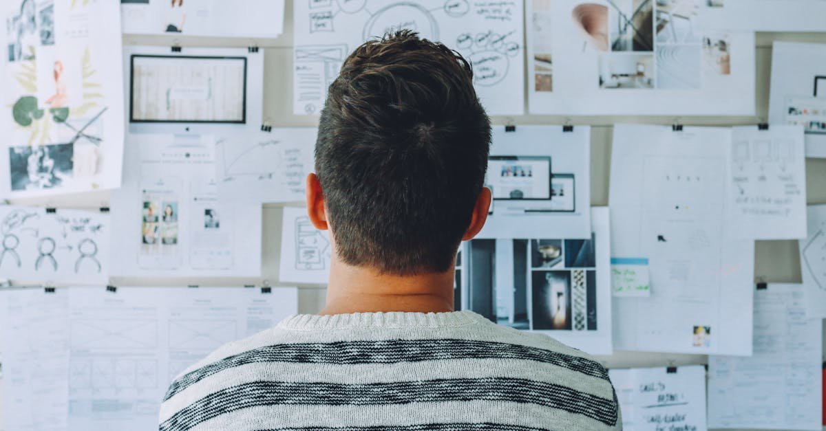 A man stands in front of a wall filled with creative ideas and plans. Ideal for innovation themes.