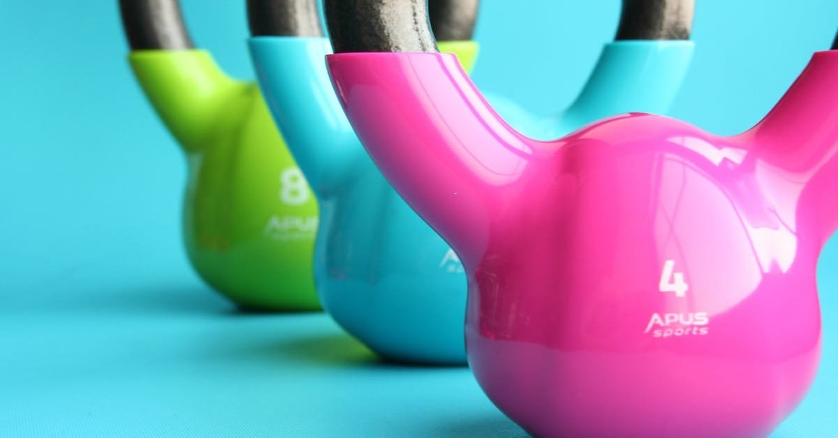 Vibrant colored kettlebells on blue background highlighting fitness and exercise equipment.