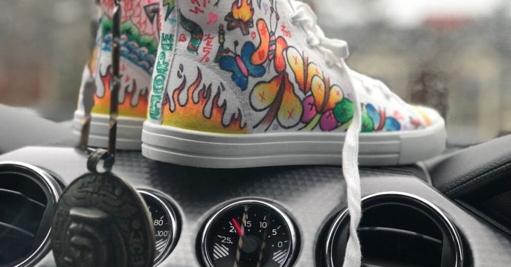 Vibrant graffiti sneakers displayed on a car dashboard, showcasing urban art style.