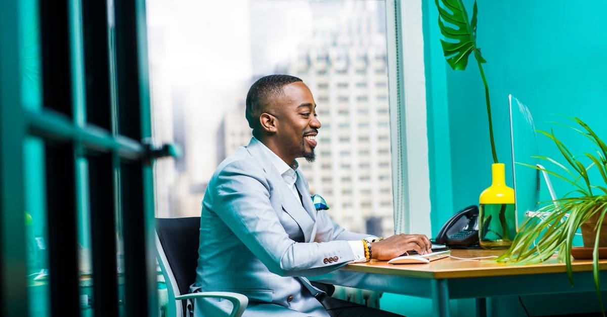Confident businessman in modern office working on laptop with city view.