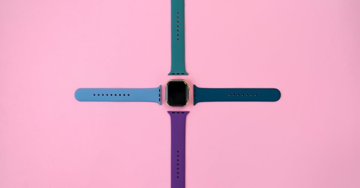 Smartwatch with colorful straps arranged on a pink background, modern and minimalist.