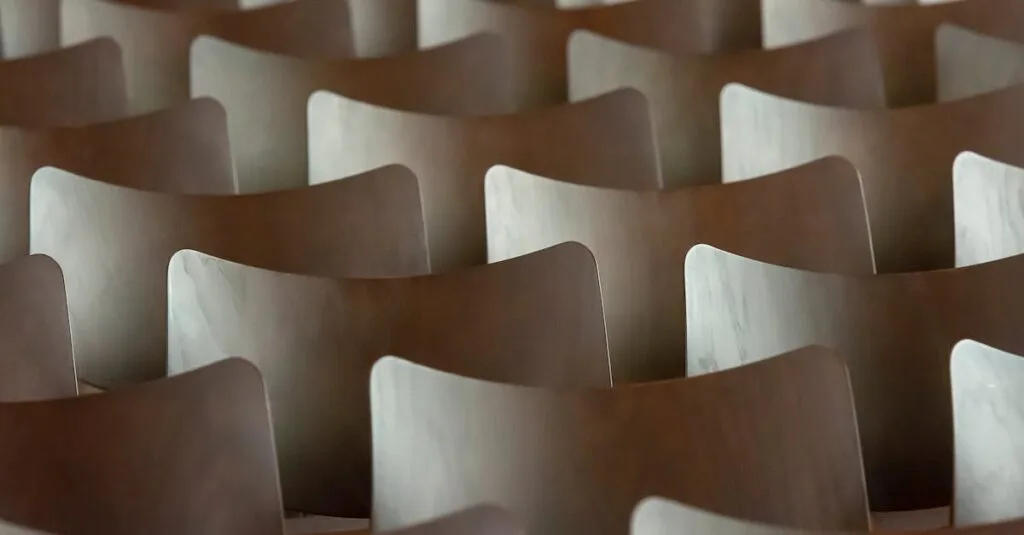 Symmetrical rows of wooden chairs creating a rhythmic and abstract pattern indoors.