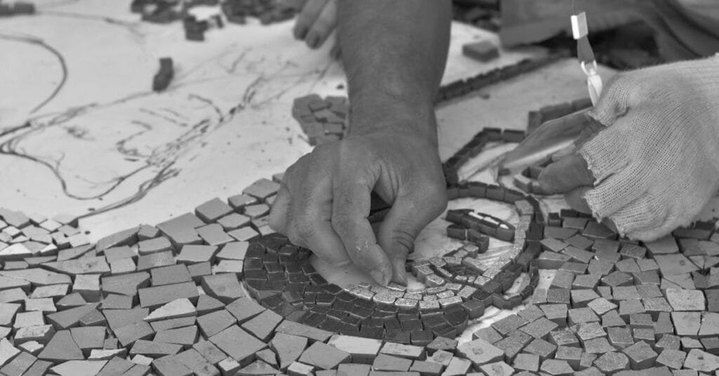 Close-up of hands meticulously crafting a mosaic, showcasing intricate artistry and craftsmanship.