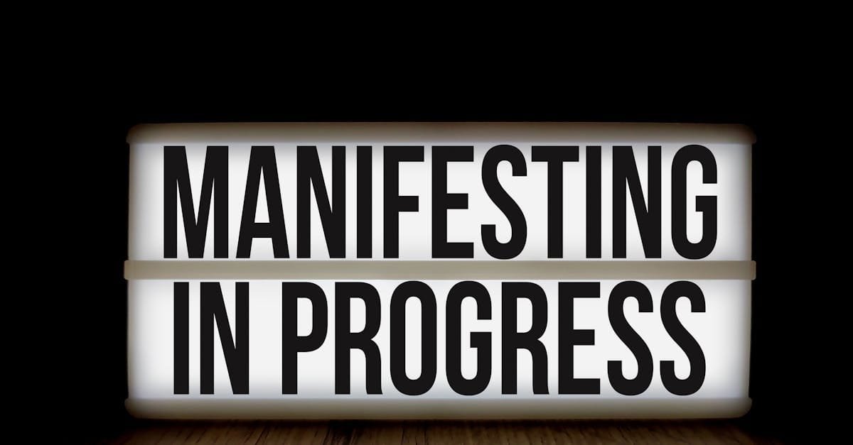 Illuminated lightbox sign with the motivational message 'Manifesting in Progress'.