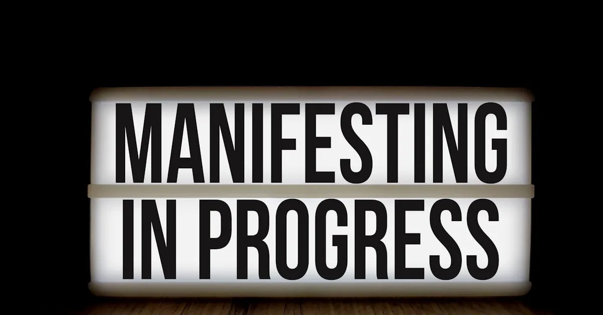 Illuminated lightbox sign with the motivational message 'Manifesting in Progress'.