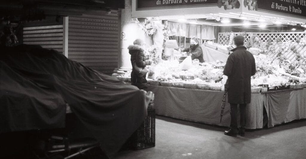 Monochrome street scene of people at a market at night.