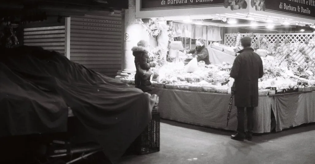 Monochrome street scene of people at a market at night.